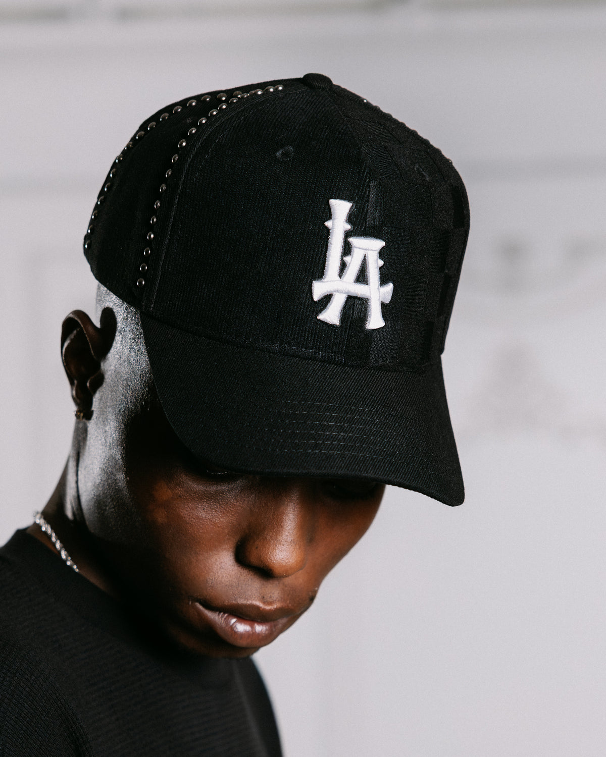 Person wearing a black cap with 'LA' logo on a neutral background